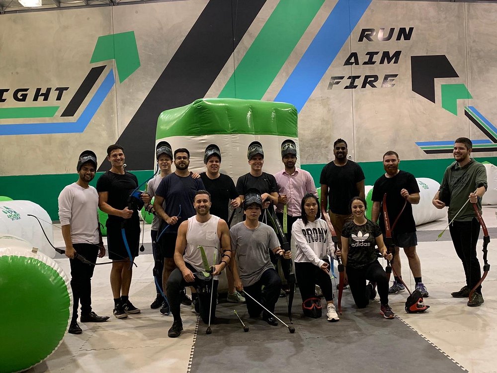 A group geared up with bows in front of the RUN AIM FIRE wall at our Reservoir, Melbourne arena