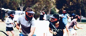 School-age players in masks aiming bows during an outdoor Arrow Tag game